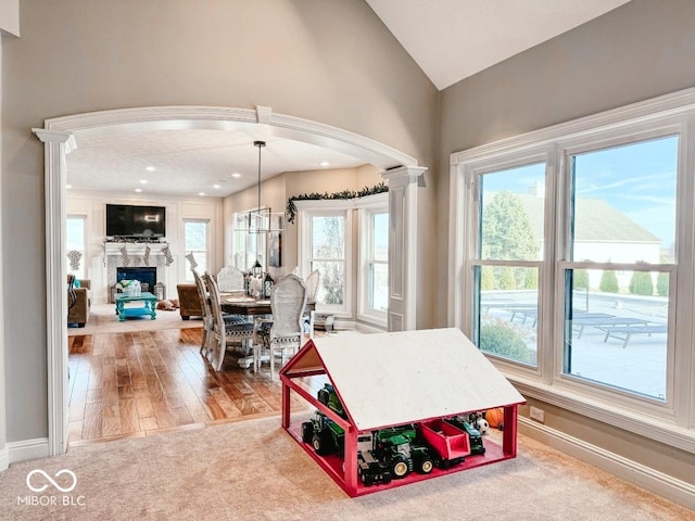 dining space featuring lofted ceiling, hardwood / wood-style floors, decorative columns, and a healthy amount of sunlight