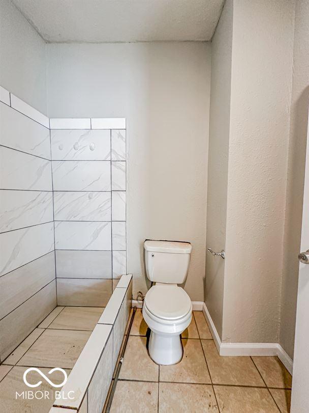 bathroom with tile patterned floors, toilet, and a shower