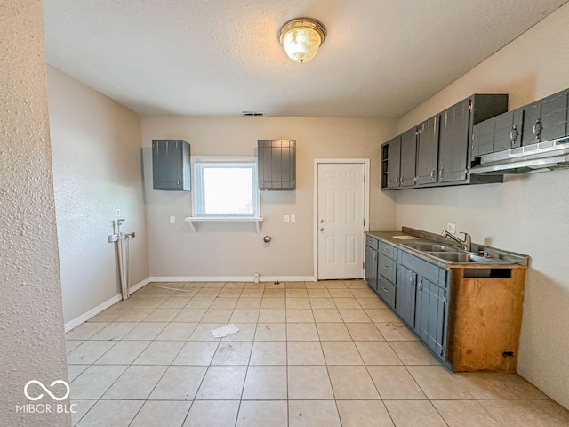 kitchen featuring light tile patterned flooring, sink, a textured ceiling, and gray cabinetry