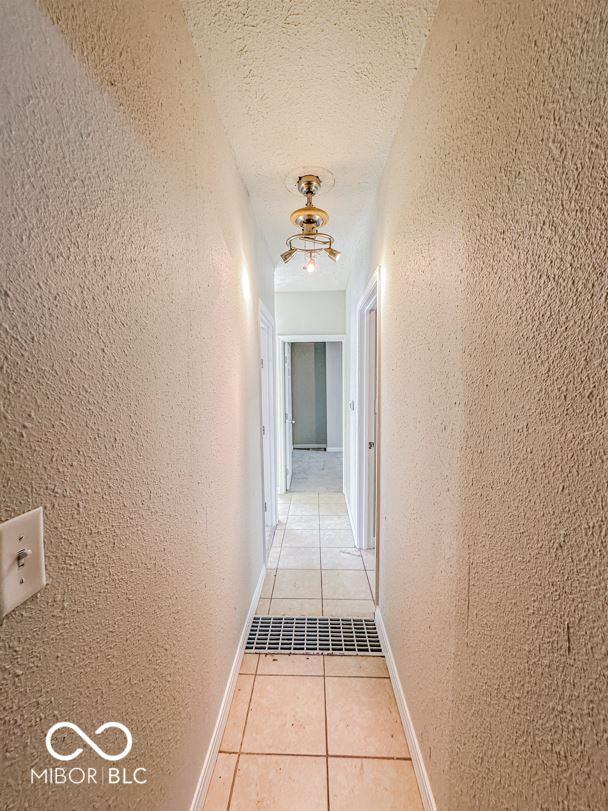 corridor featuring light tile patterned floors and a textured ceiling