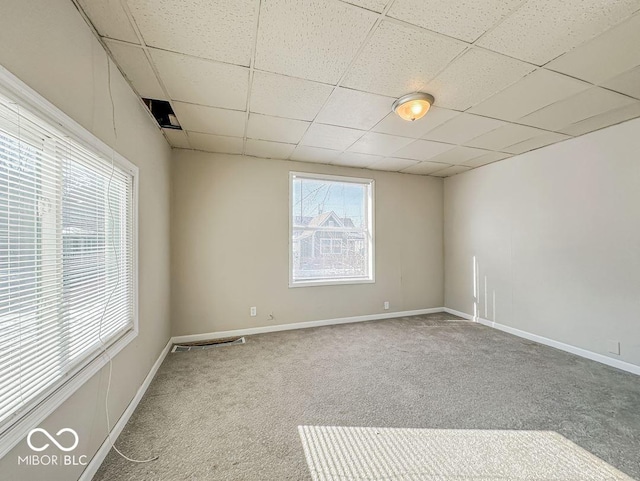 carpeted empty room with a paneled ceiling