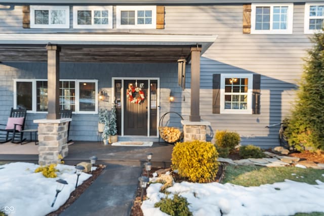 snow covered property entrance with covered porch