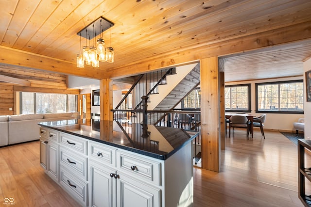 kitchen featuring wood ceiling, a center island, hanging light fixtures, a notable chandelier, and white cabinets