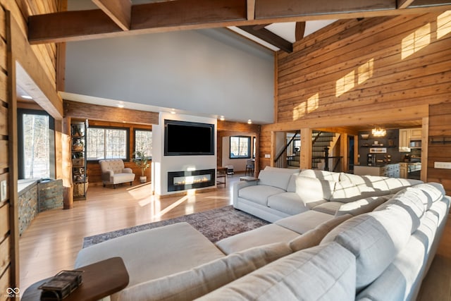 living room with beamed ceiling, wooden walls, high vaulted ceiling, and light wood-type flooring