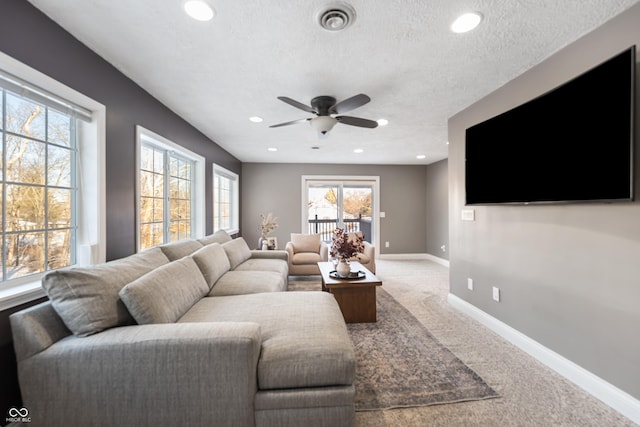 carpeted living room with ceiling fan and a textured ceiling