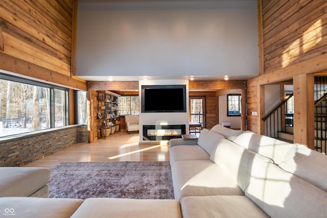 living room with a towering ceiling, rustic walls, and light hardwood / wood-style floors