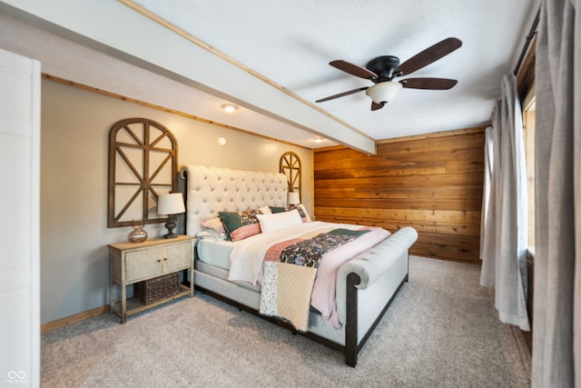 bedroom with beamed ceiling, ceiling fan, wooden walls, and light carpet