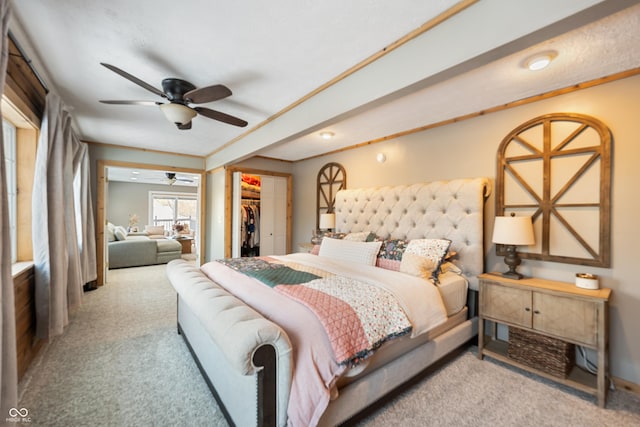 bedroom with a walk in closet, light carpet, ceiling fan, and a closet