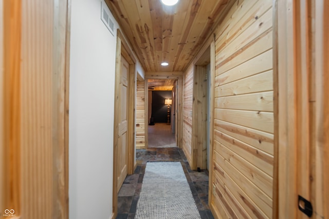 hallway featuring wood ceiling and wood walls