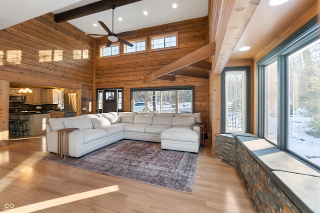 living room with ceiling fan, wood walls, a healthy amount of sunlight, and light wood-type flooring