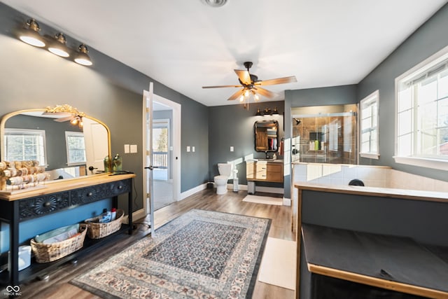 bathroom with hardwood / wood-style flooring, vanity, walk in shower, ceiling fan, and toilet