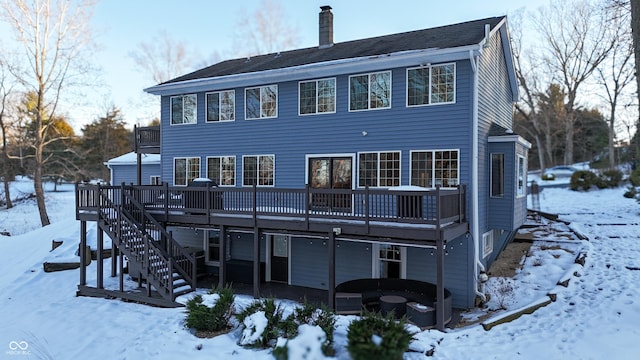 snow covered rear of property with a wooden deck