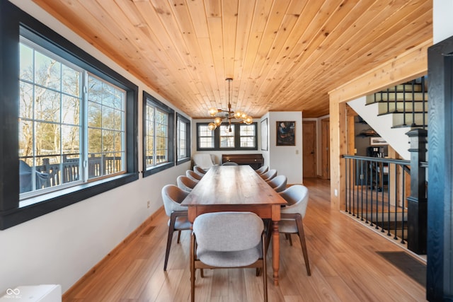 dining area with a healthy amount of sunlight, an inviting chandelier, wooden ceiling, and light wood-type flooring