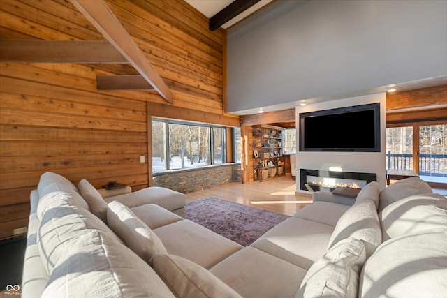 living room featuring wooden walls, high vaulted ceiling, beam ceiling, and light hardwood / wood-style floors