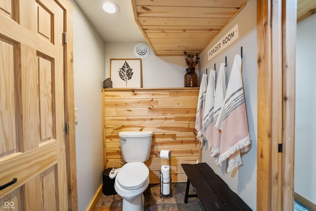 bathroom with toilet, wood ceiling, and wood walls