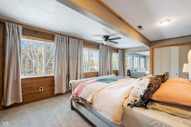 carpeted bedroom with wooden walls and ceiling fan