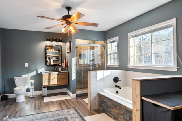 bathroom with hardwood / wood-style floors, shower with separate bathtub, toilet, and ceiling fan