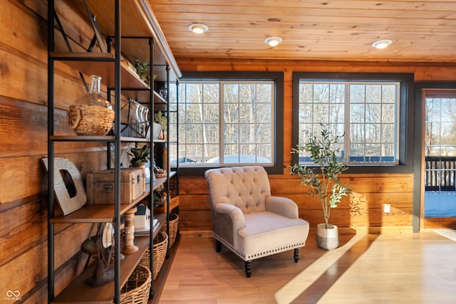 sitting room featuring light hardwood / wood-style flooring, wooden walls, wooden ceiling, and plenty of natural light