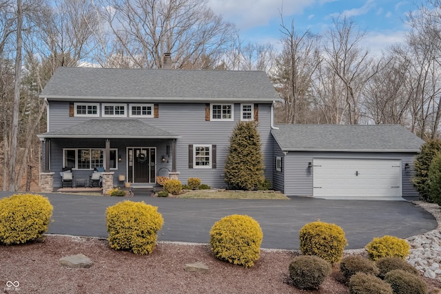 view of front of house with aphalt driveway, roof with shingles, a chimney, a porch, and an attached garage