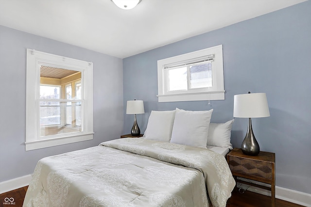 bedroom with multiple windows and dark hardwood / wood-style floors