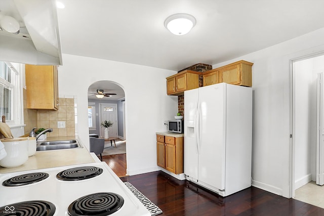 kitchen featuring sink, white appliances, ceiling fan, dark hardwood / wood-style floors, and decorative backsplash