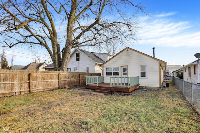 back of property with a deck and a lawn