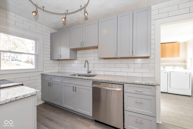 kitchen with dishwasher, sink, washing machine and dryer, and gray cabinetry