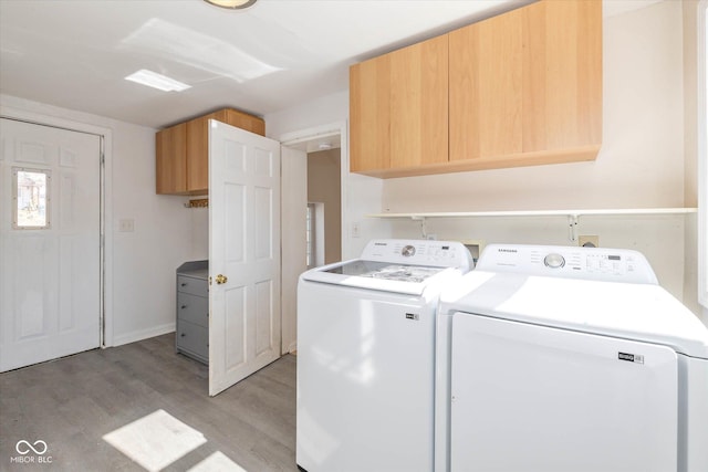 washroom featuring washing machine and dryer, cabinets, and light wood-type flooring