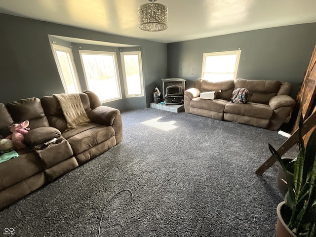 living room featuring plenty of natural light, carpet floors, and a wood stove