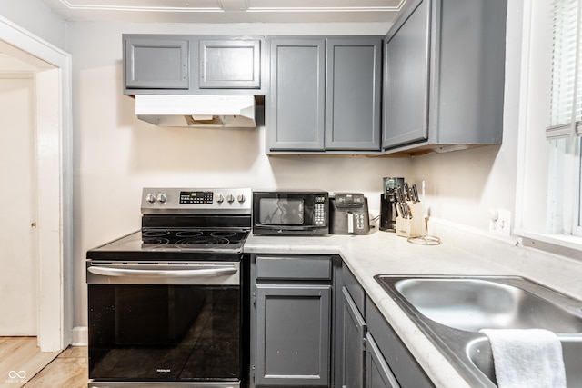361 S Spencer Ave, Indianapolis, IN 46219 - kitchen with stainless steel electric range oven, under cabinet range hood, gray cabinetry, black microwave, and a sink