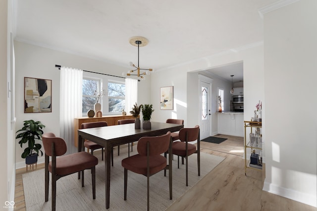 dining space featuring an inviting chandelier, ornamental molding, plenty of natural light, and light hardwood / wood-style floors