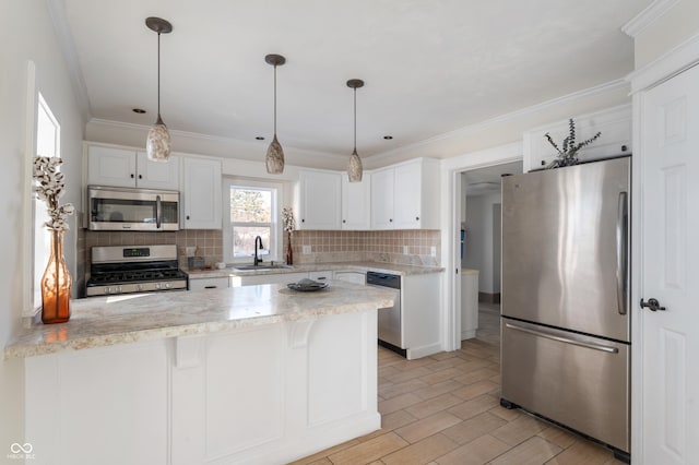 kitchen with appliances with stainless steel finishes, sink, white cabinets, and a kitchen breakfast bar