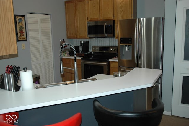 kitchen with appliances with stainless steel finishes, backsplash, and kitchen peninsula