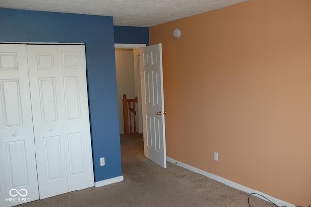 unfurnished bedroom with carpet flooring, a textured ceiling, and a closet