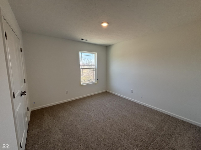 unfurnished bedroom featuring dark colored carpet, baseboards, and a textured ceiling