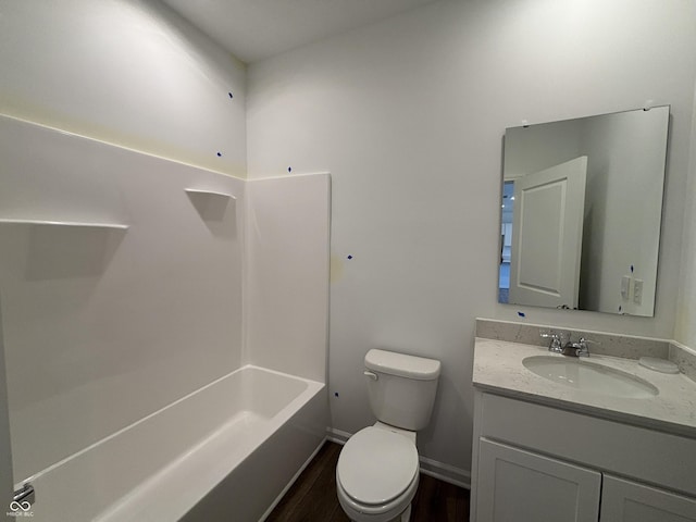 bathroom with vanity, wood finished floors, baseboards, shower / washtub combination, and toilet