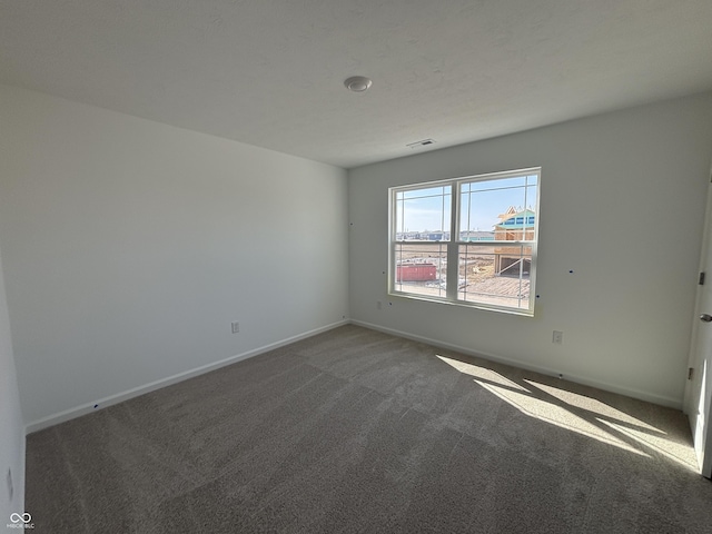 empty room featuring visible vents, baseboards, and carpet