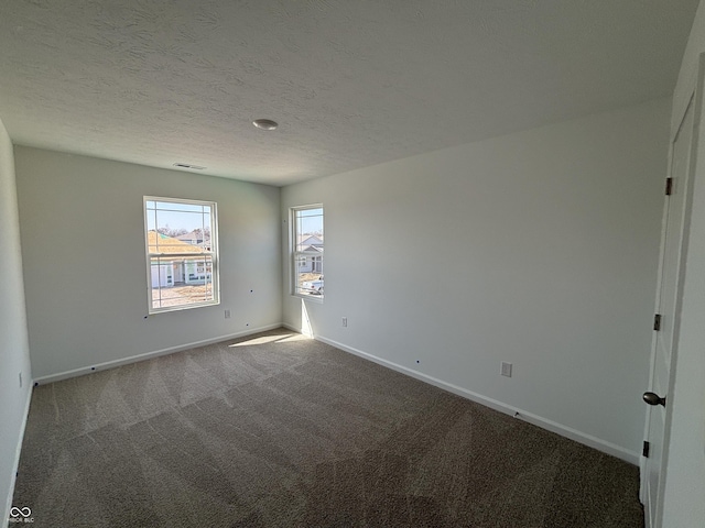 carpeted spare room with visible vents, a textured ceiling, and baseboards