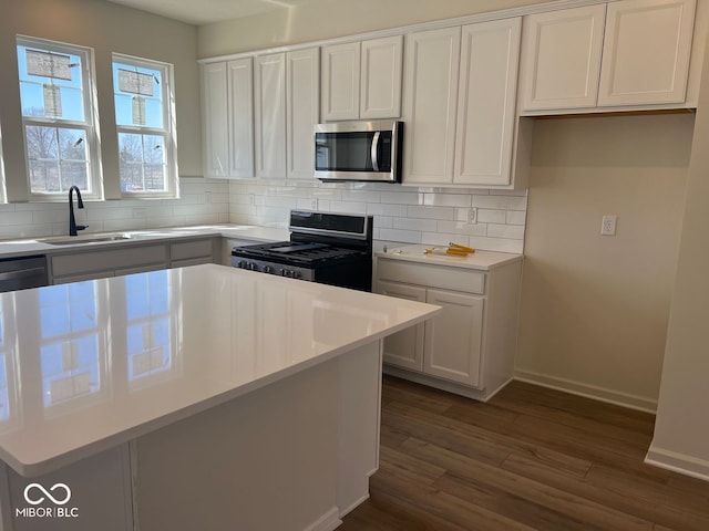 kitchen featuring sink, dark wood-type flooring, appliances with stainless steel finishes, backsplash, and white cabinets