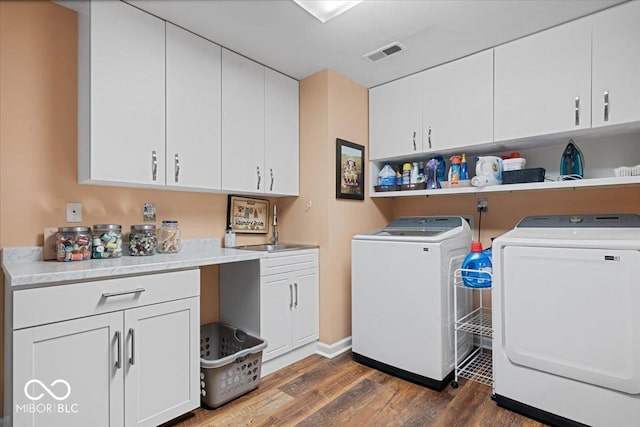 washroom with cabinets, washer and dryer, and dark hardwood / wood-style flooring