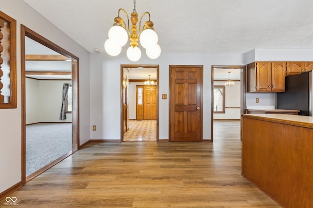 kitchen featuring stainless steel refrigerator, pendant lighting, and an inviting chandelier