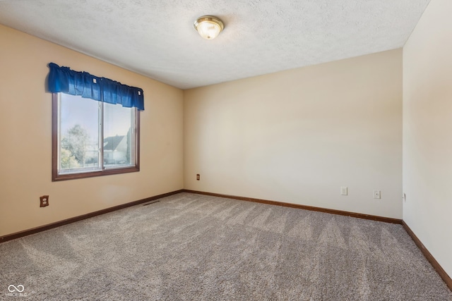 empty room with carpet floors and a textured ceiling