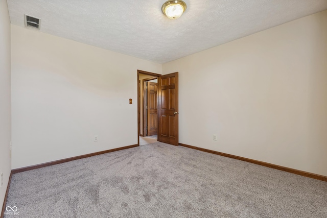 carpeted empty room featuring a textured ceiling