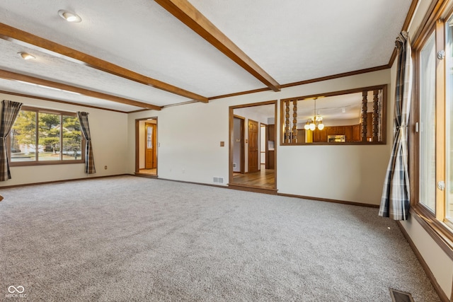 carpeted spare room with beamed ceiling, ornamental molding, a notable chandelier, and a textured ceiling