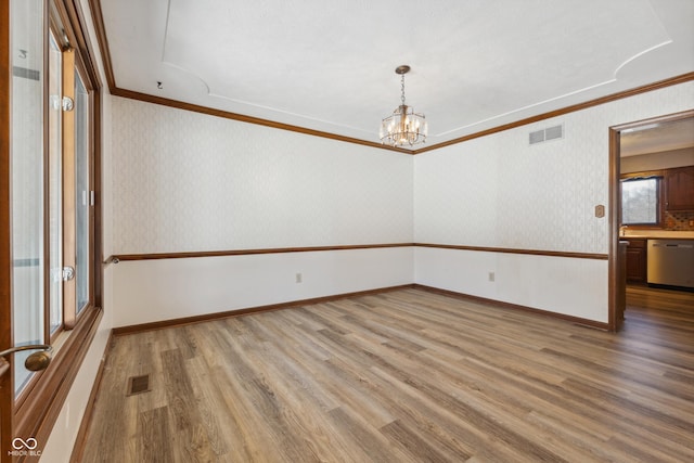 spare room featuring hardwood / wood-style flooring, crown molding, and a chandelier