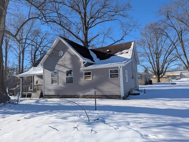 snow covered back of property with a porch