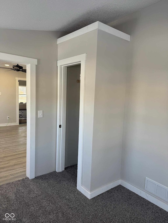 unfurnished room featuring dark carpet and a textured ceiling