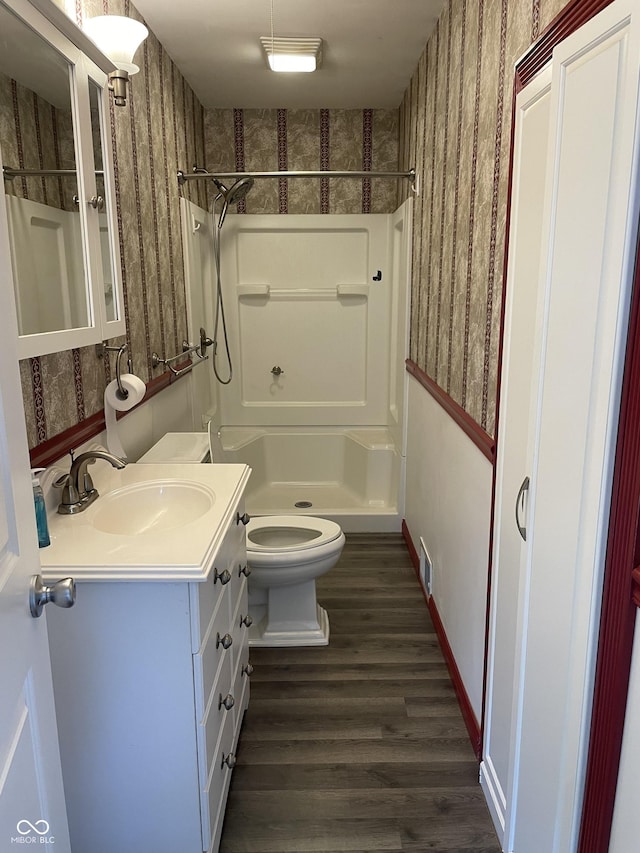 bathroom featuring hardwood / wood-style flooring, vanity, toilet, and a shower