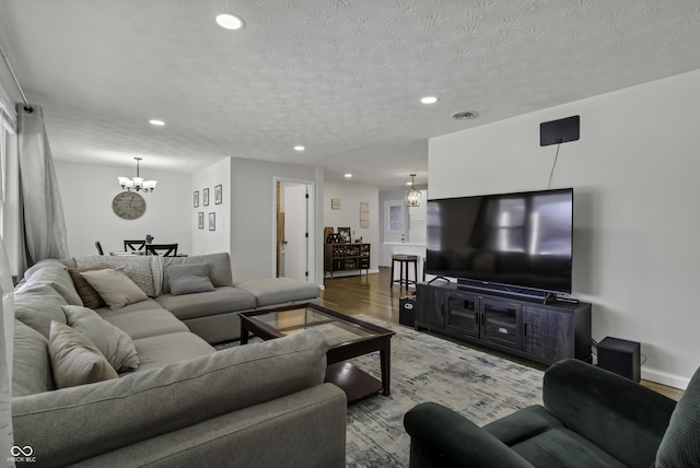 living room featuring light hardwood / wood-style flooring, a chandelier, and a textured ceiling