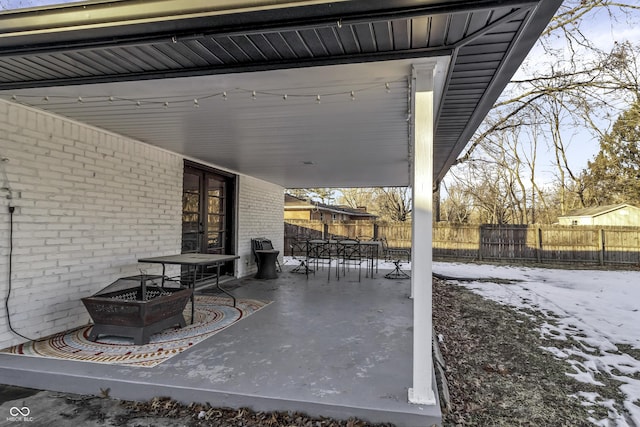 snow covered patio featuring an outdoor fire pit